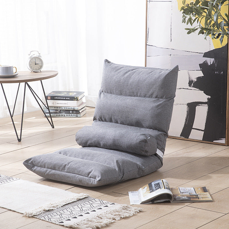 Gray floor pillow in a room with a table, books, and a plant
