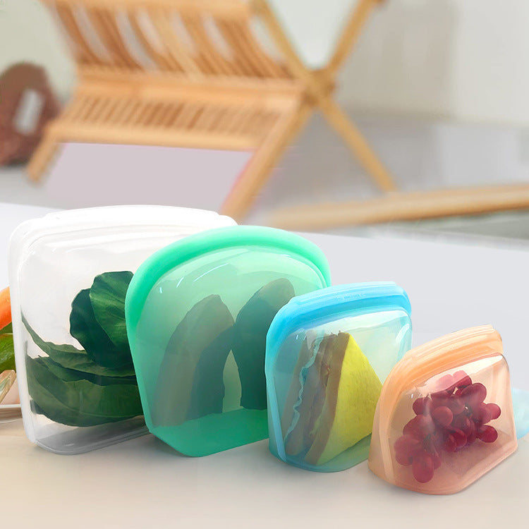 Set of colorful silicone food storage containers on a white surface with a blurred background; Oversized reusable silicone storage bags in assorted colors