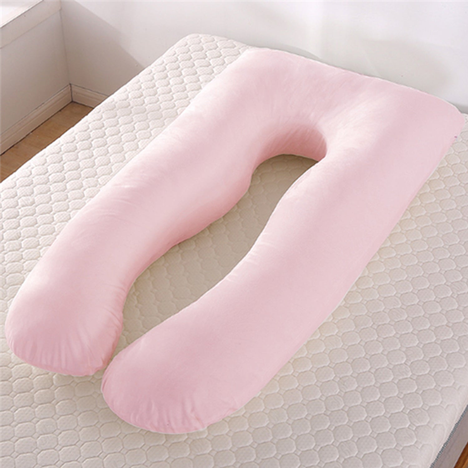 Pink U-shaped body pillow on a textured surface