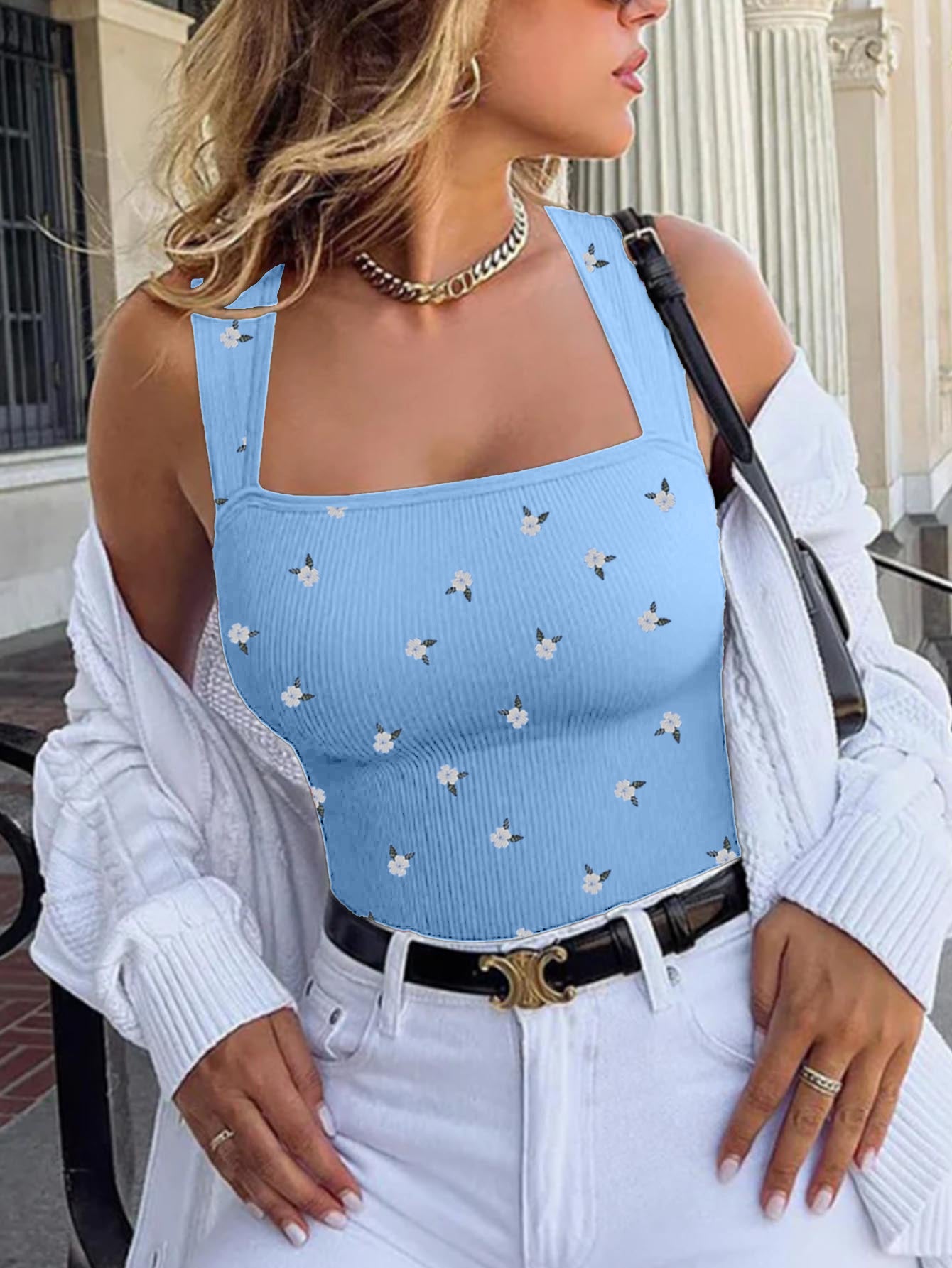 Woman wearing a blue studded romper jumpsuit with white pants outdoors