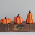 Three decorative Halloween pumpkins on an old book with a gray background
