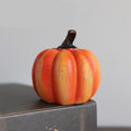 Small orange Halloween pumpkin Decor light with a cracked texture on a gray surface