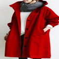 Person wearing a red coat with a hood on a plain background