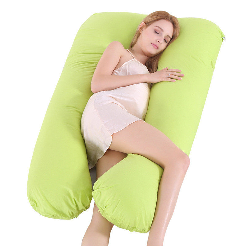 Woman lying on a green U-shaped body pillow on a white background