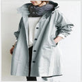 Person wearing a long gray hooded waterproof windbreaker on a plain background