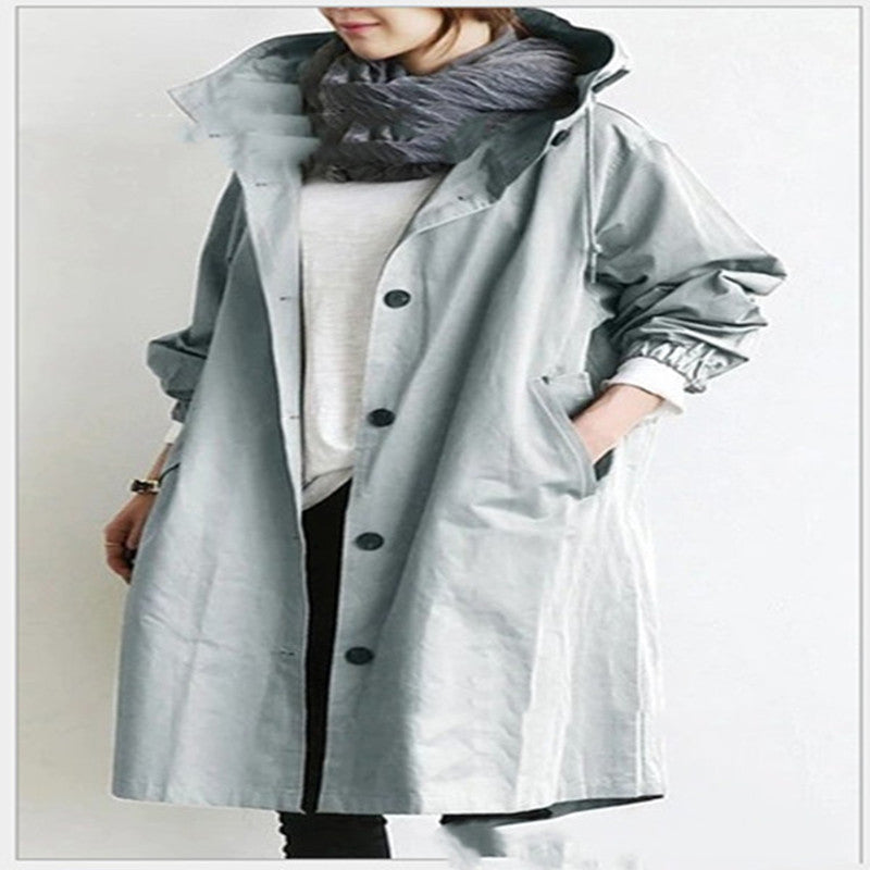 Person wearing a long gray hooded waterproof windbreaker on a plain background