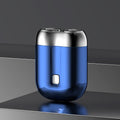 Blue electric shaver with silver top on a reflective surface